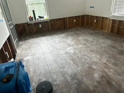 Room with wet drywall removed and an air mover drying the floor