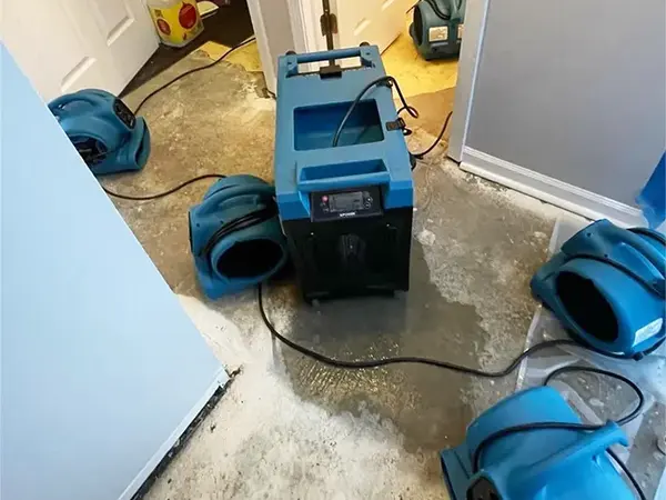 Dehumidifier and air movers running on a wet concrete floor